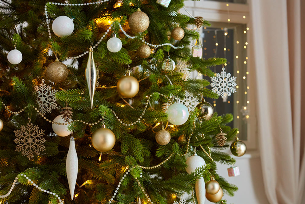 Коледна елха с орнаменти в златно, сребърно и бяло.