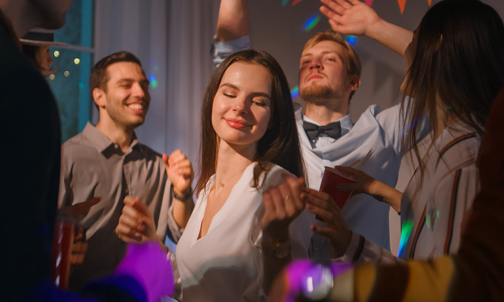 Група хора, танцуващи на парти, сред които е жена, наслаждаваща се на музиката..