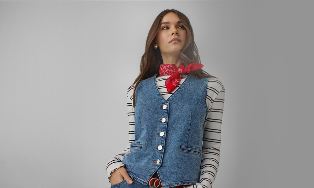 Жената в синьо дънково жилетче и червена кърпа около врата.